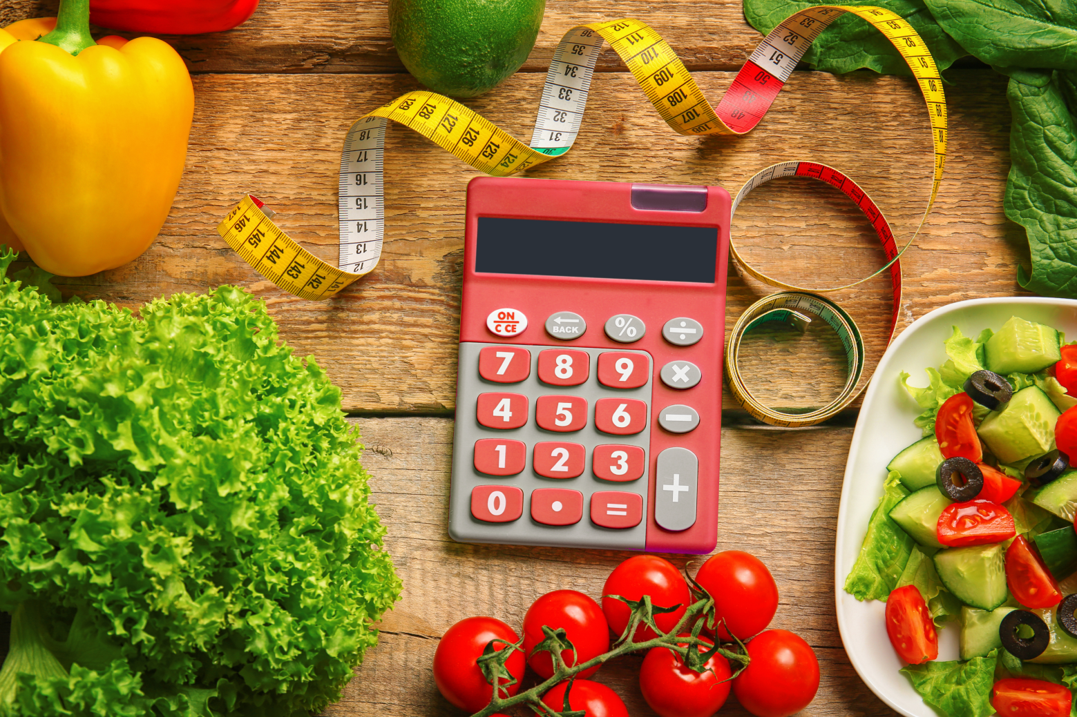 red calculator surrounded by vegetables and a tape measurer
